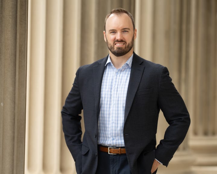 Photograph of former State Department employee Mike Johnson with white doric columns in the background.